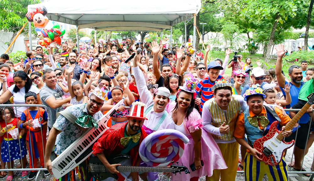 banda em cima de palco e plateia atrás posando para a foto